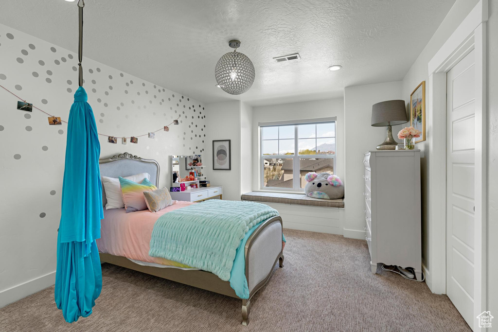 Carpeted bedroom with a textured ceiling, baseboards, and visible vents