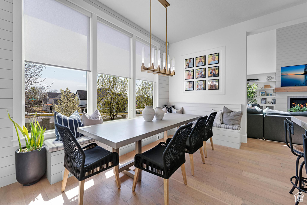 Dining room with plenty of natural light, light wood-style flooring, and a lit fireplace
