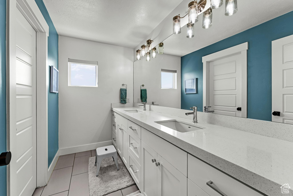 Full bathroom featuring double vanity, a sink, tile patterned flooring, and baseboards