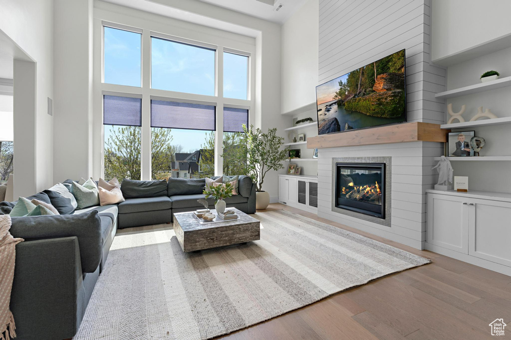 Living area with a high ceiling, wood finished floors, and a glass covered fireplace
