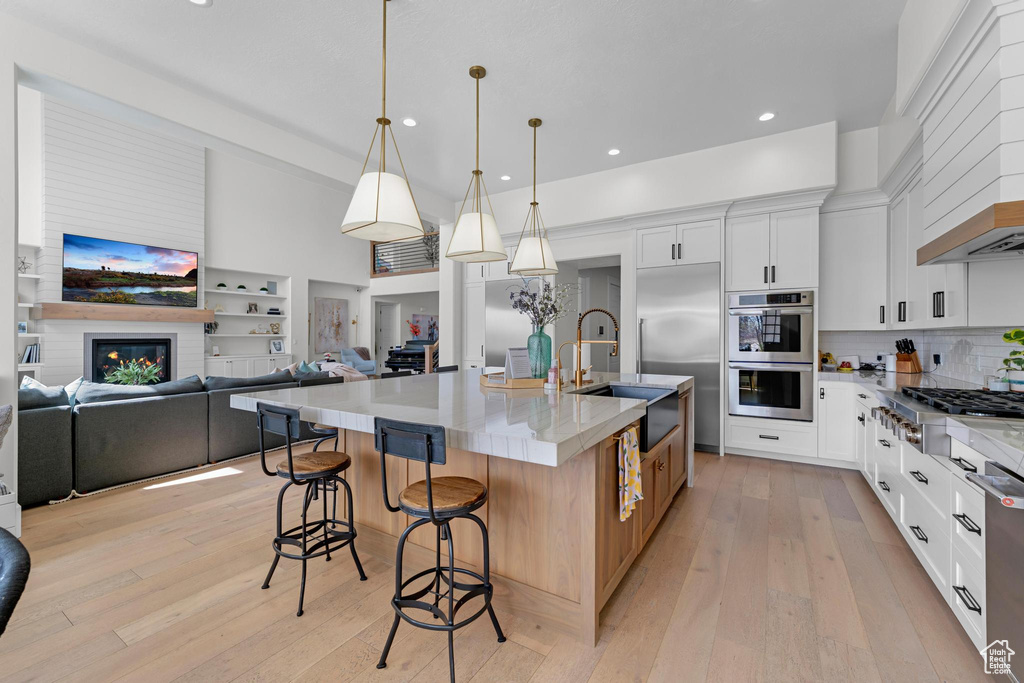 Kitchen with a sink, open floor plan, light wood-style flooring, and appliances with stainless steel finishes