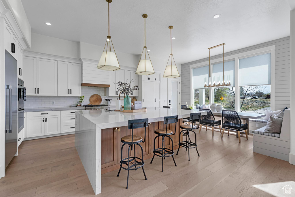 Kitchen with tasteful backsplash, light wood-style flooring, light countertops, and stainless steel oven