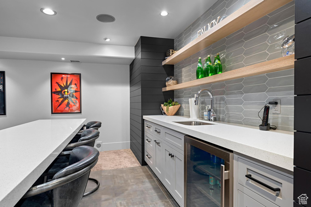 Bar featuring indoor wet bar, decorative backsplash, a sink, and beverage cooler