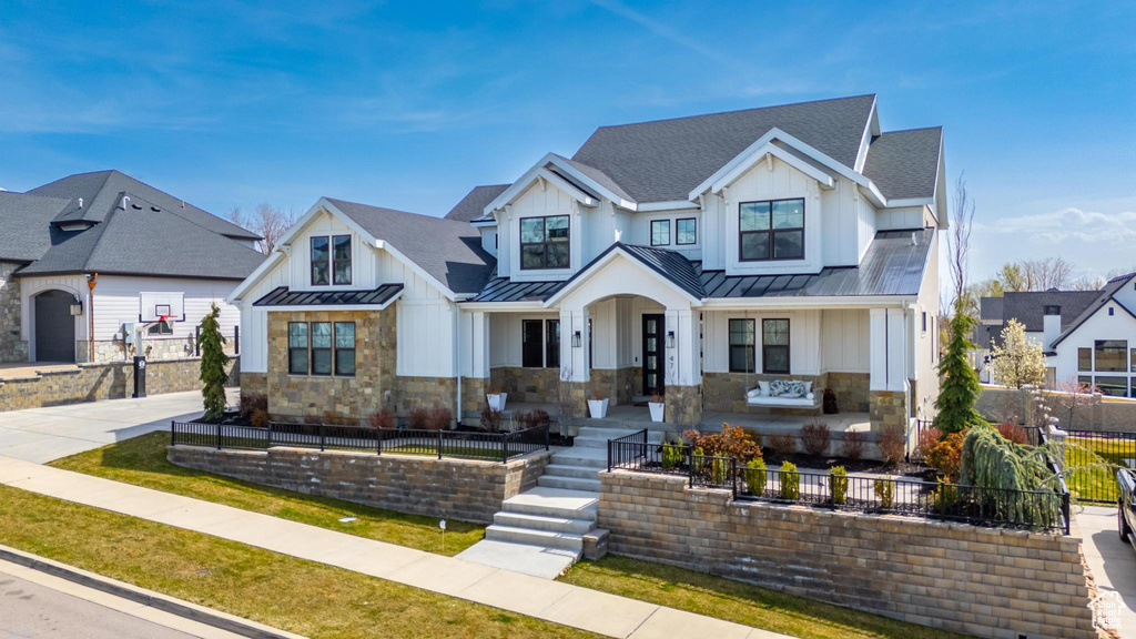 Modern inspired farmhouse with a standing seam roof, fence, stone siding, and metal roof