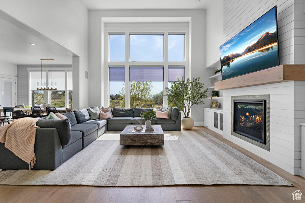 Living room featuring an inviting chandelier, hardwood / wood-style floors, a towering ceiling, and a fireplace