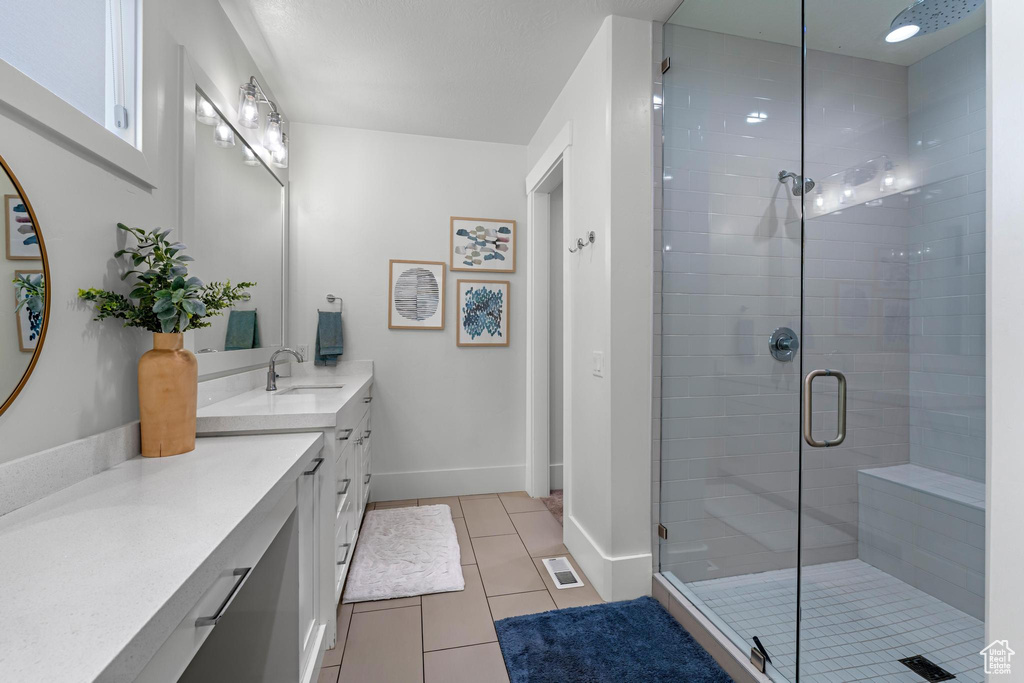 Full bathroom featuring vanity, tile patterned flooring, visible vents, a stall shower, and baseboards