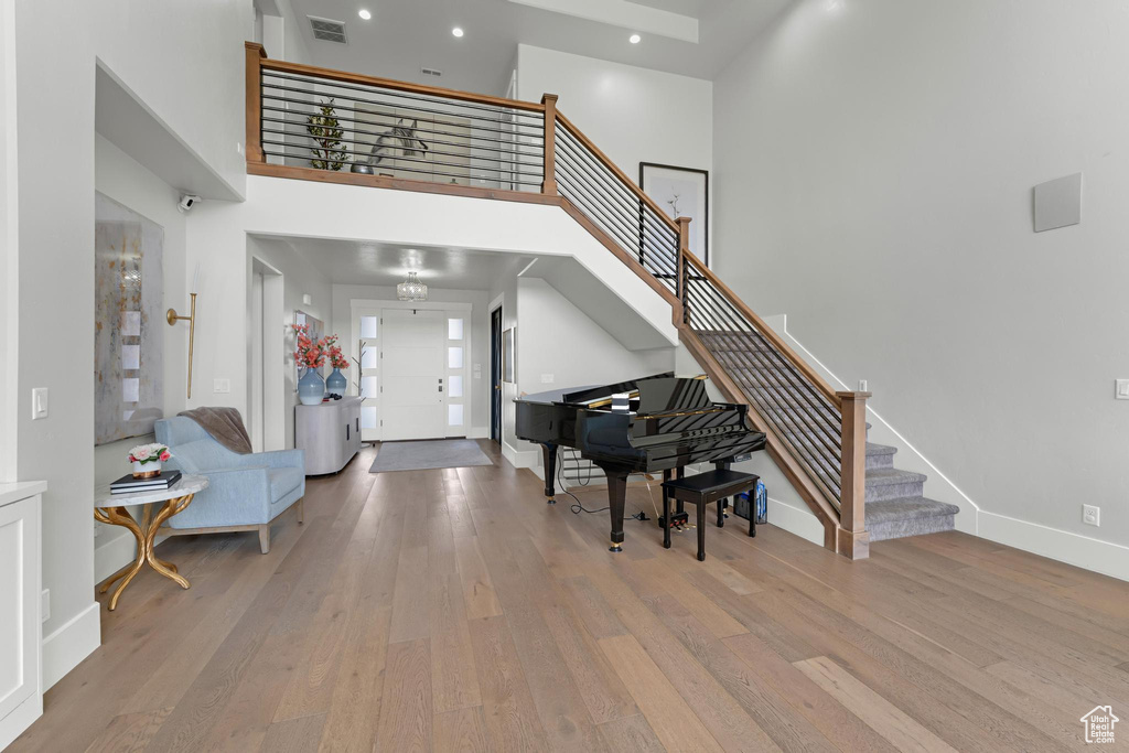 Foyer entrance featuring visible vents, baseboards, a high ceiling, stairway, and wood finished floors