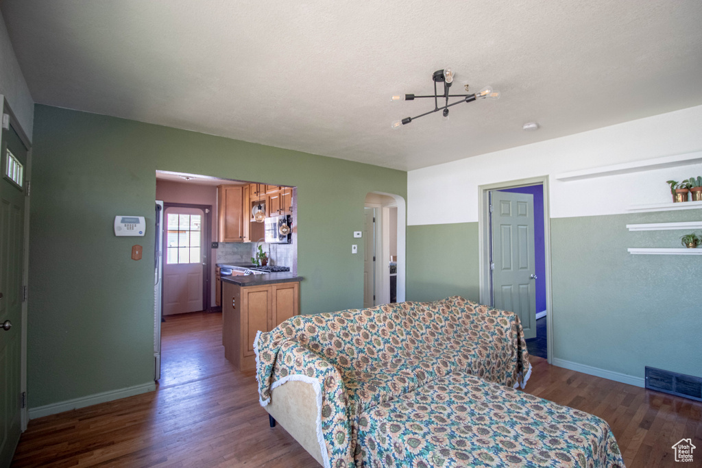 Bedroom with arched walkways, wood finished floors, baseboards, and visible vents