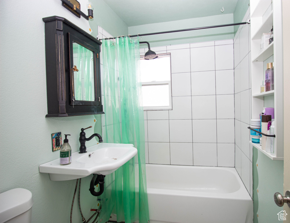 Bathroom featuring toilet and shower / bathtub combination with curtain