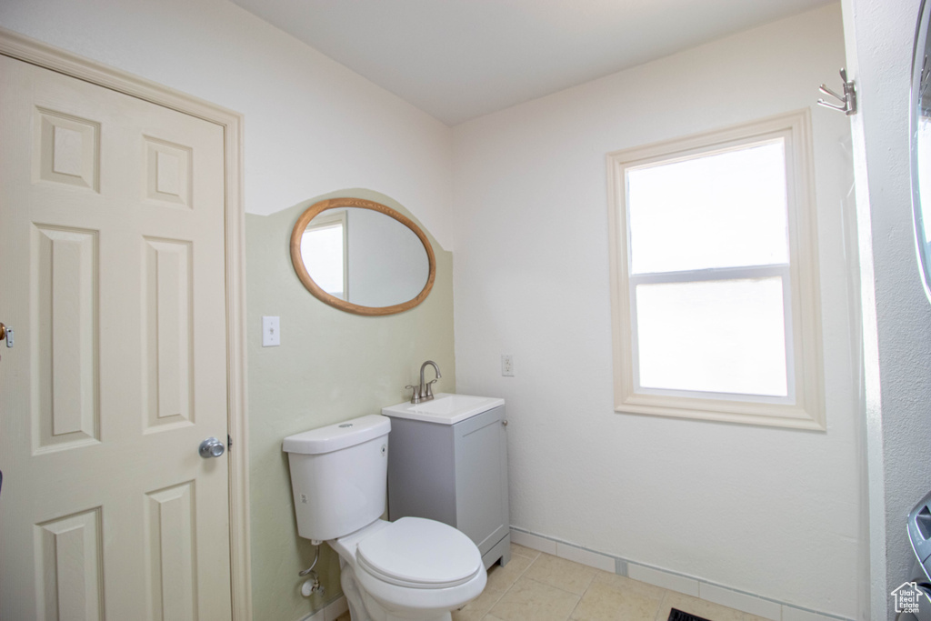 Bathroom featuring toilet, tile patterned floors, vanity, and baseboards