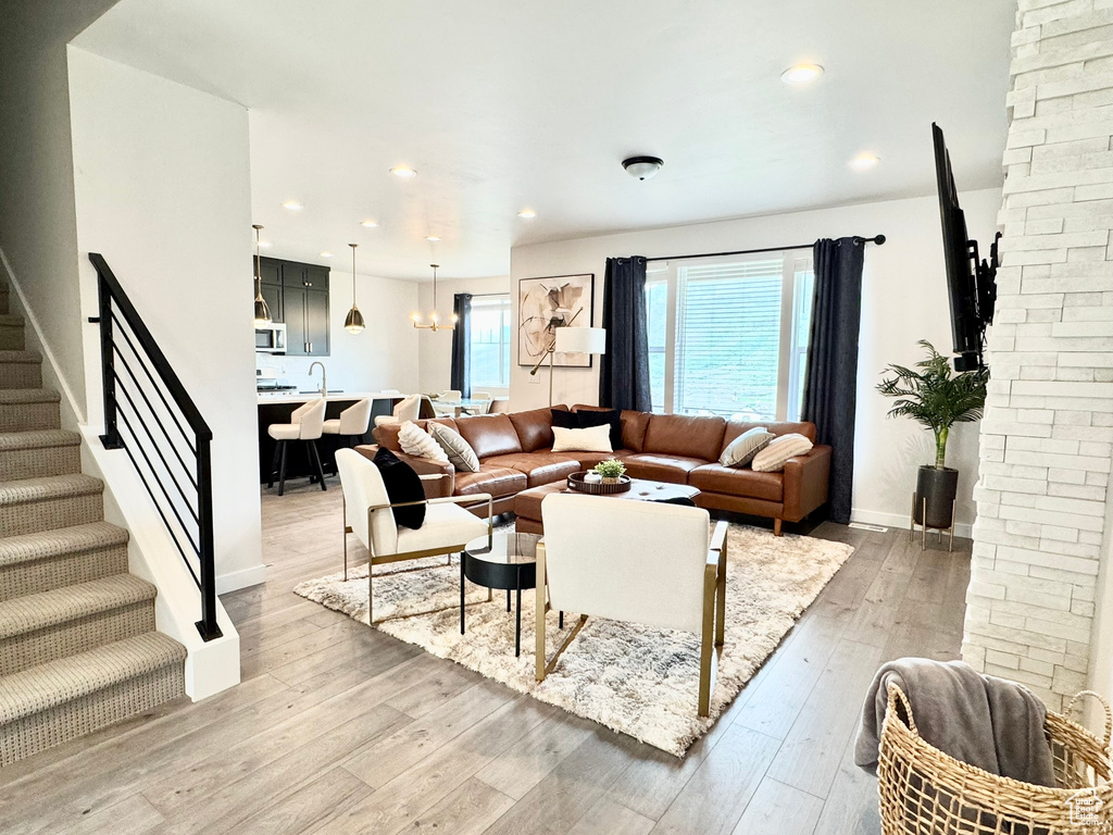Living room with light wood-style flooring, stairs, baseboards, and recessed lighting