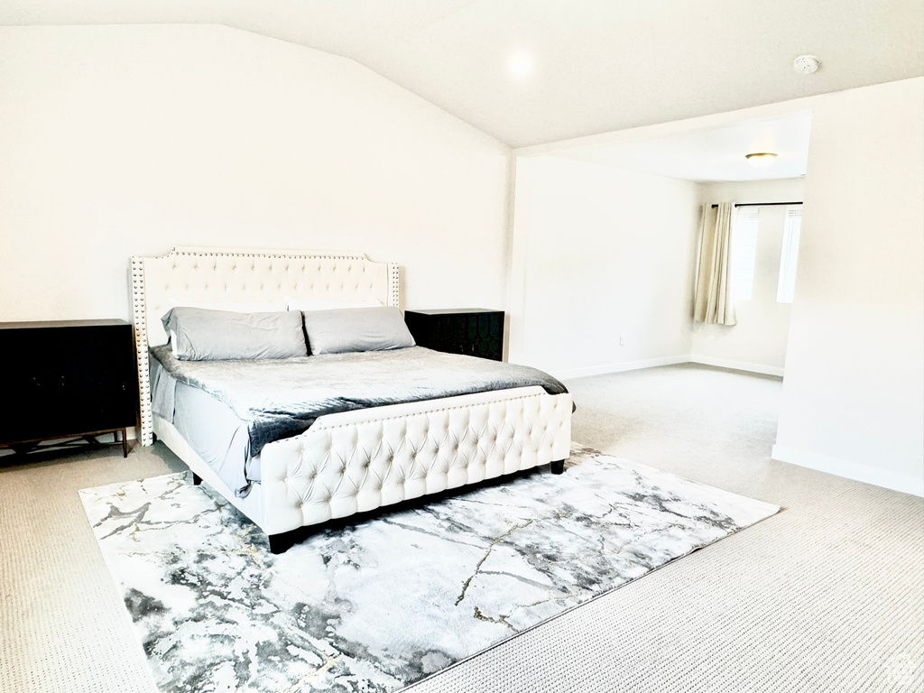 Bedroom with carpet flooring, vaulted ceiling, and baseboards