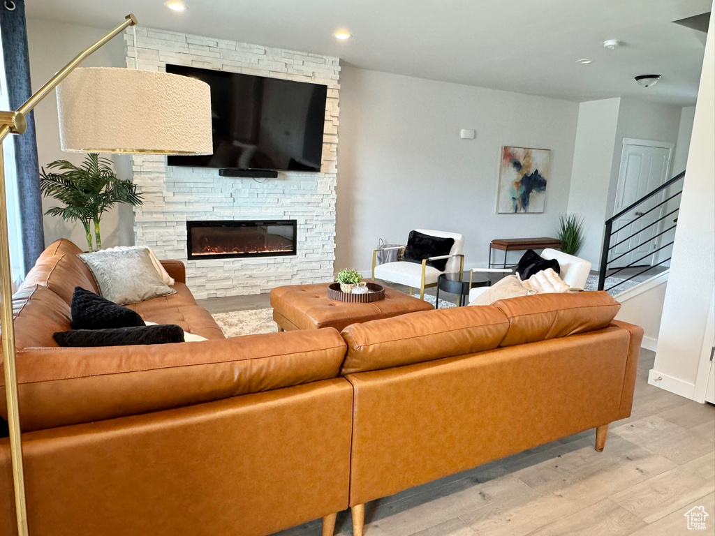 Living room featuring wood finished floors, a fireplace, recessed lighting, stairway, and baseboards