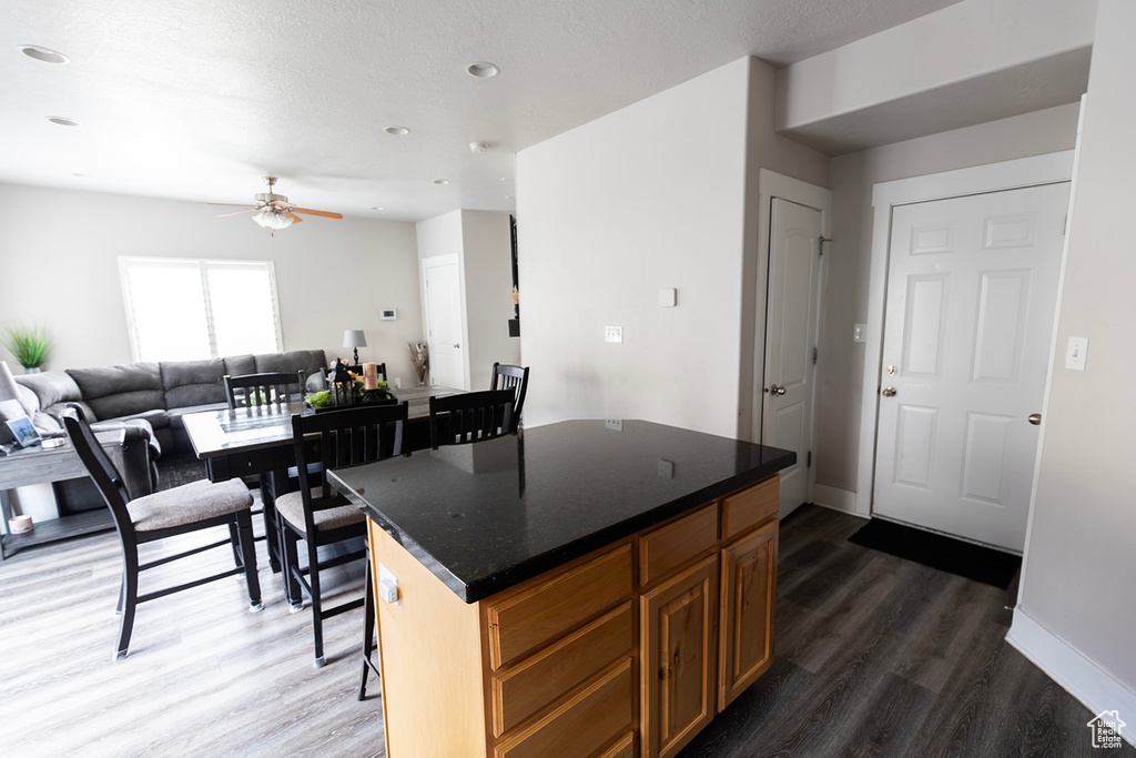 Kitchen with dark wood-type flooring, a center island, baseboards, and ceiling fan