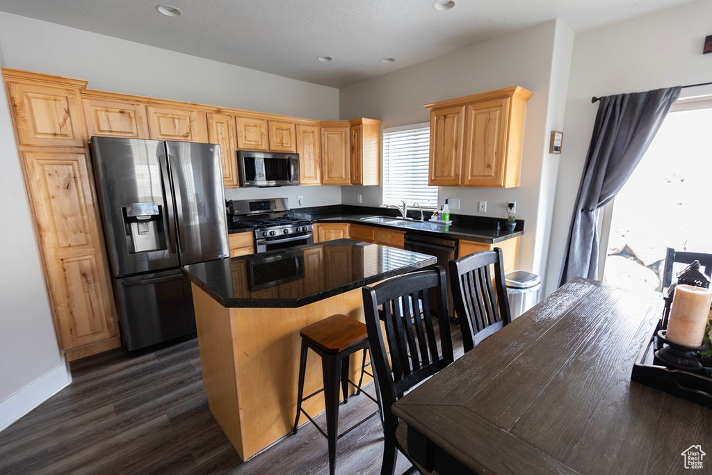 Kitchen featuring recessed lighting, a kitchen island, stainless steel appliances, a breakfast bar area, and dark wood-style floors