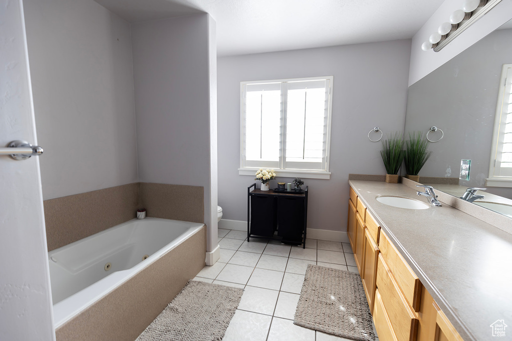 Full bathroom with baseboards, toilet, a tub with jets, vanity, and tile patterned floors