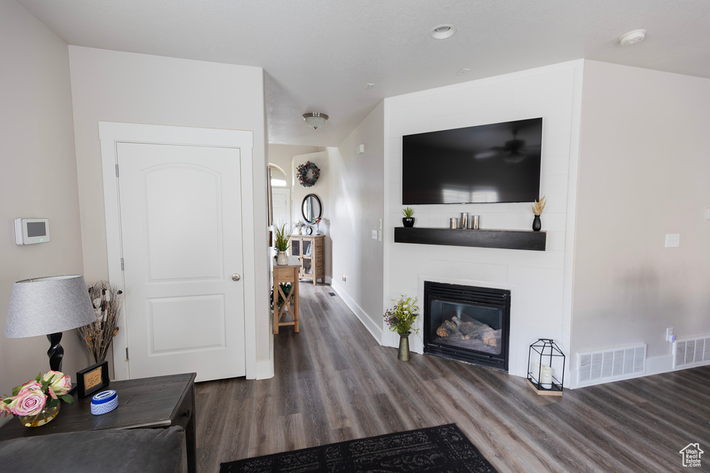 Living room featuring visible vents, a large fireplace, baseboards, and wood finished floors