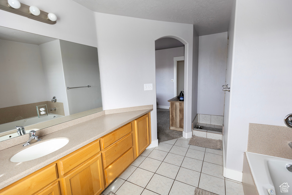 Full bathroom featuring tile patterned floors, vanity, baseboards, and a garden tub