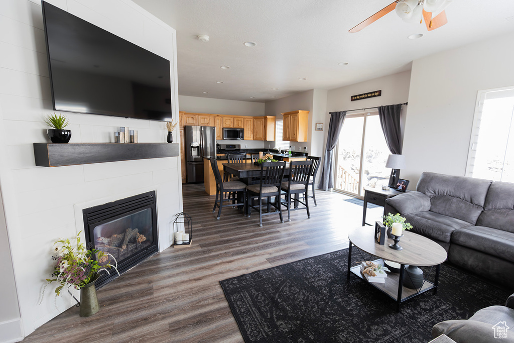 Living area with ceiling fan, recessed lighting, a glass covered fireplace, and wood finished floors