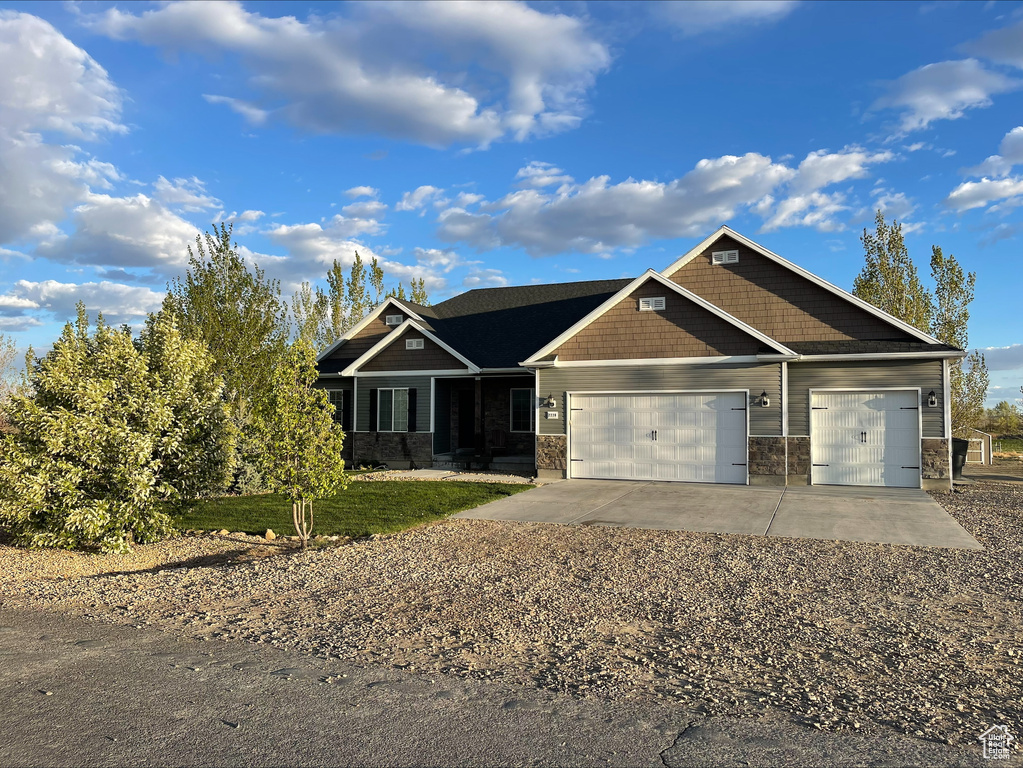 Craftsman-style home featuring a garage, concrete driveway, and stone siding