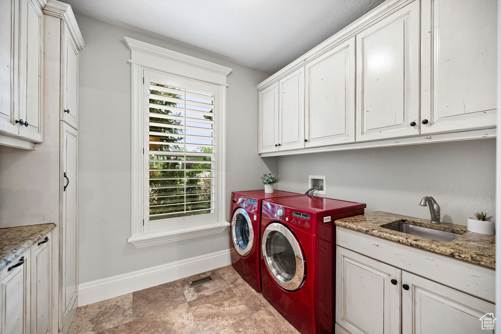 Laundry room with cabinet space, washing machine and clothes dryer, and stone finish floors