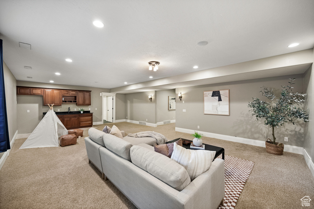 Living area featuring light colored carpet, recessed lighting, and wet bar