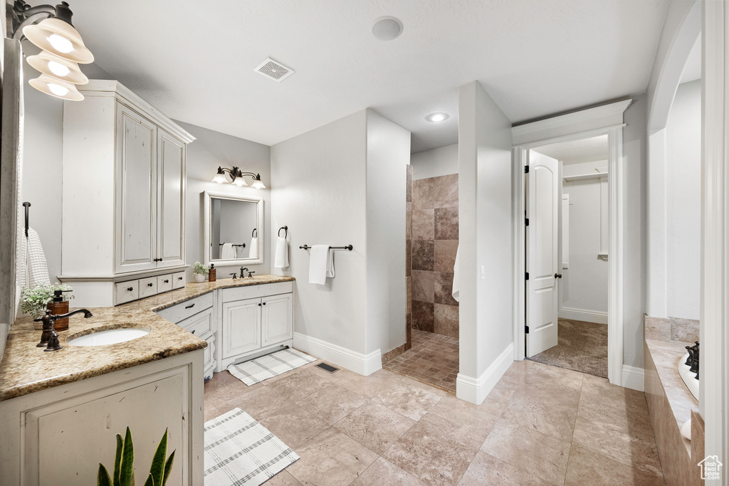 Full bathroom with two vanities, walk in shower, and a garden tub