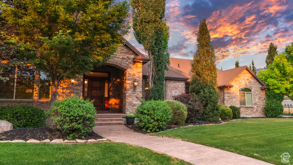View of front of home with a front lawn, stone siding, and brick siding