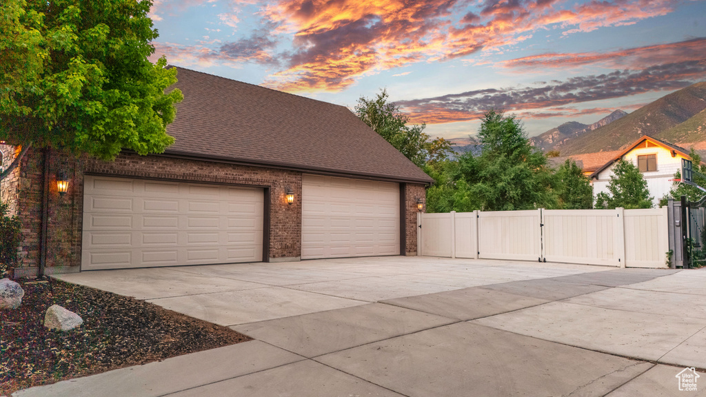 Garage at dusk featuring driveway and a gate