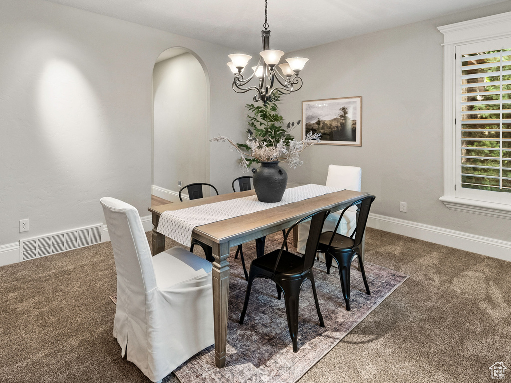Dining space with carpet, a chandelier, arched walkways, and recessed lighting