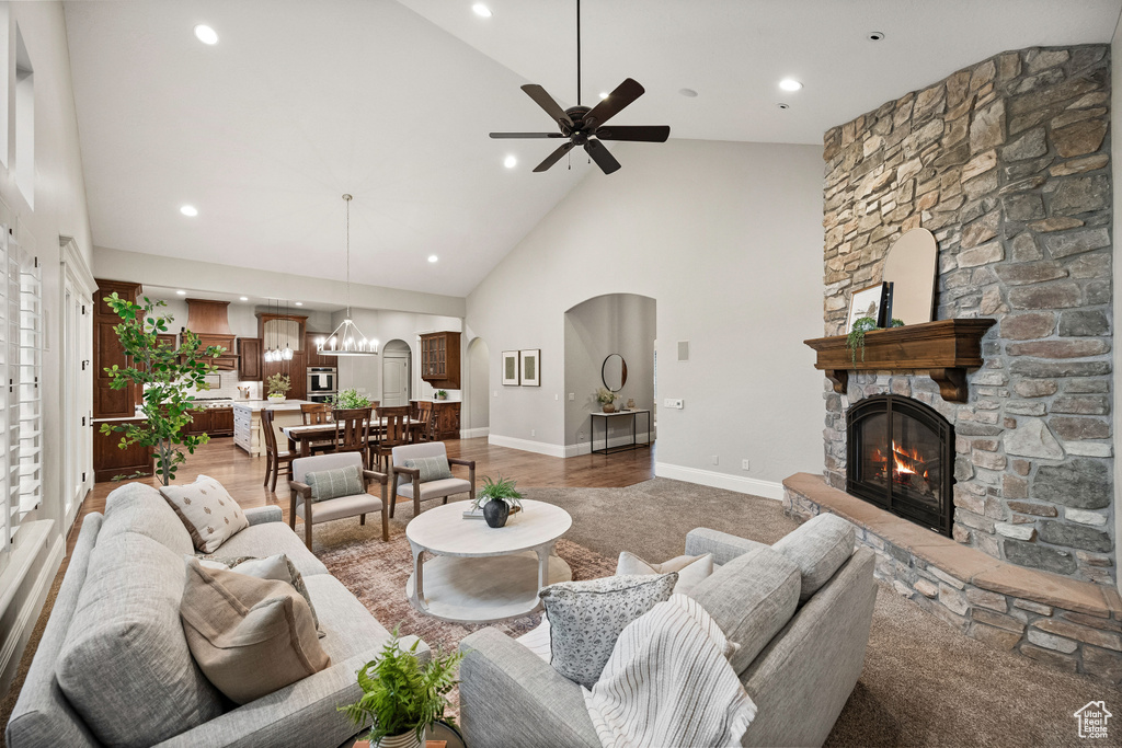 Living area with a fireplace, arched walkways, high vaulted ceiling, a ceiling fan, and recessed lighting