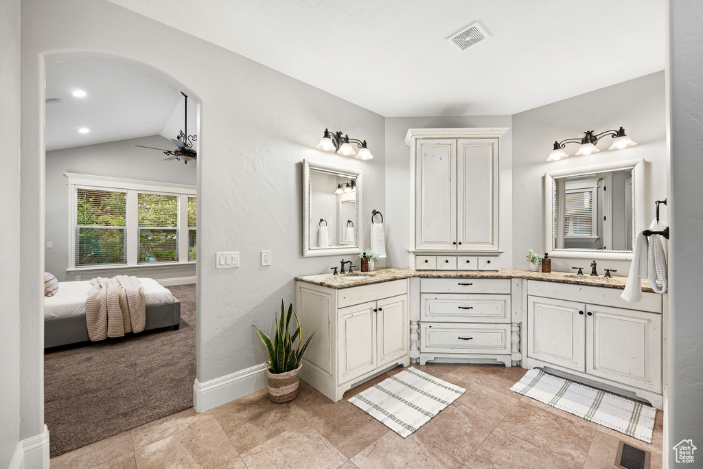 Ensuite bathroom featuring double vanity, vaulted ceiling, and ceiling fan