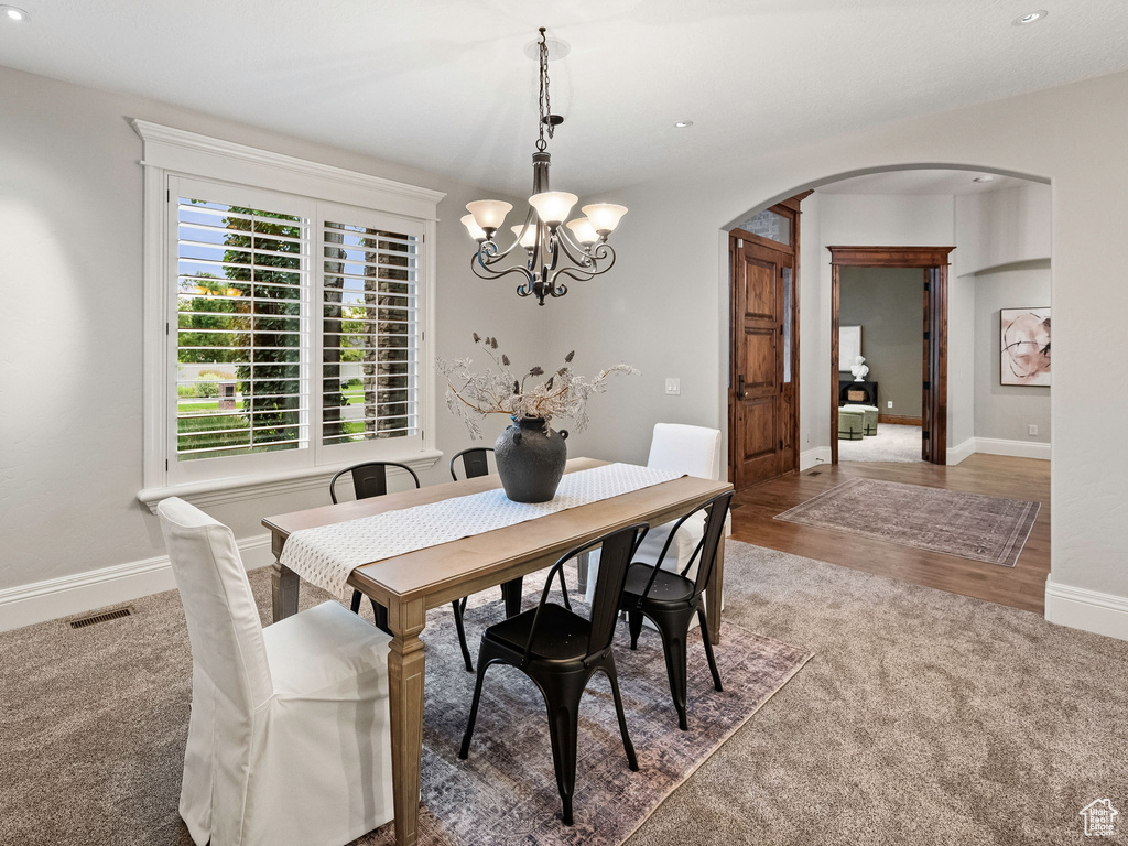 Dining room featuring arched walkways, carpet, a chandelier, and recessed lighting