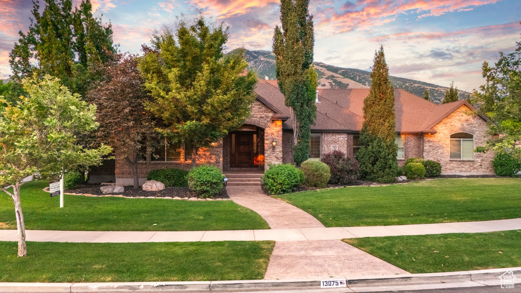 View of front of house with a front lawn, stone siding, and brick siding