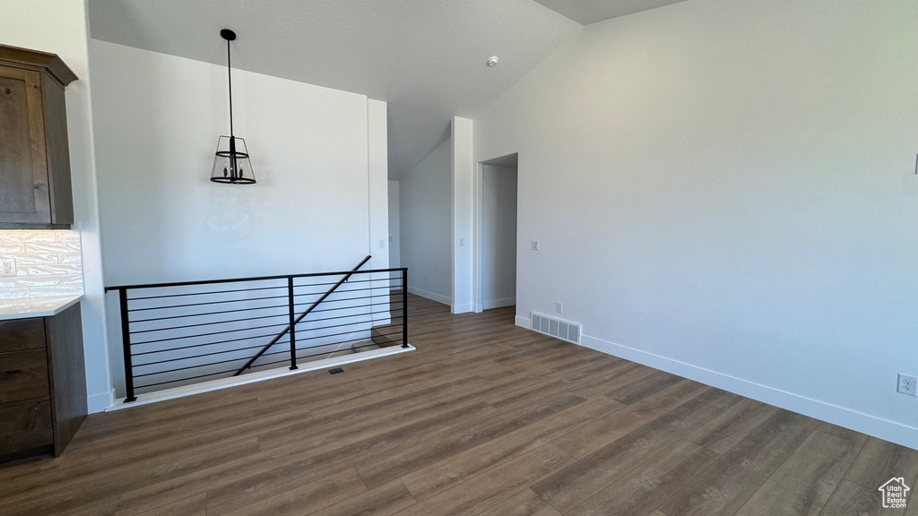 Unfurnished room featuring wood finished floors, lofted ceiling, and baseboards