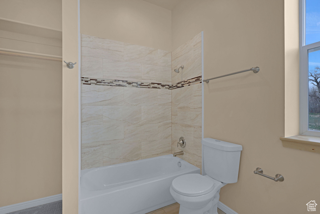 Full bath featuring washtub / shower combination, baseboards, and toilet