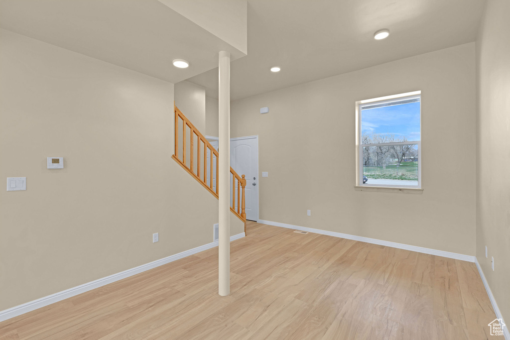Spare room featuring baseboards, light wood-type flooring, recessed lighting, and stairs
