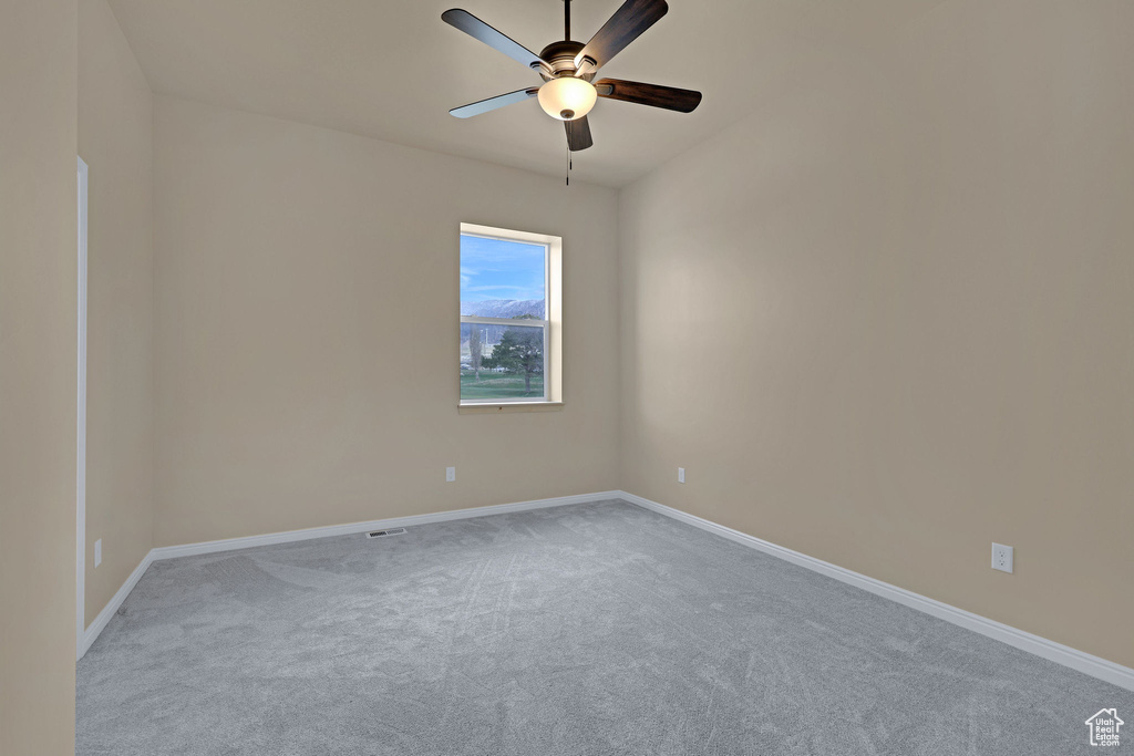 Spare room featuring ceiling fan, light colored carpet, and baseboards