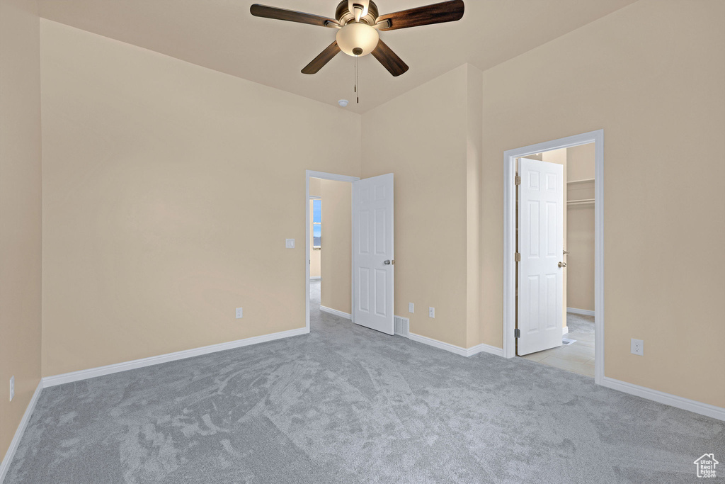 Unfurnished bedroom with ceiling fan, carpet flooring, baseboards, and a spacious closet