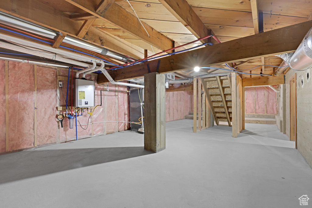 Unfinished below grade area featuring stairway and water heater