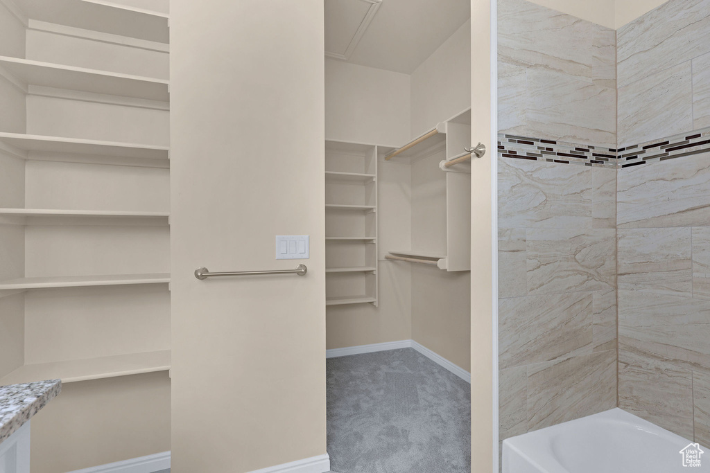 Bathroom with a walk in closet, shower / bath combination, and baseboards