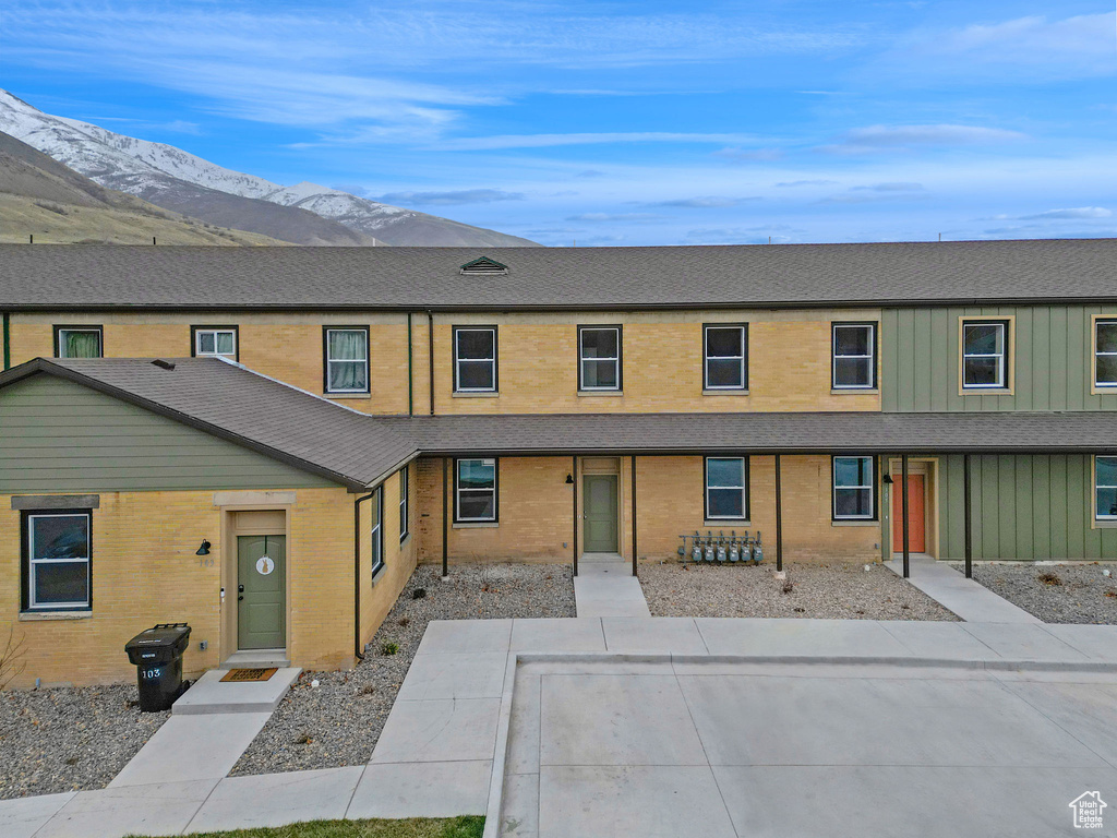 Multi unit property featuring brick siding, roof with shingles, and a mountain view