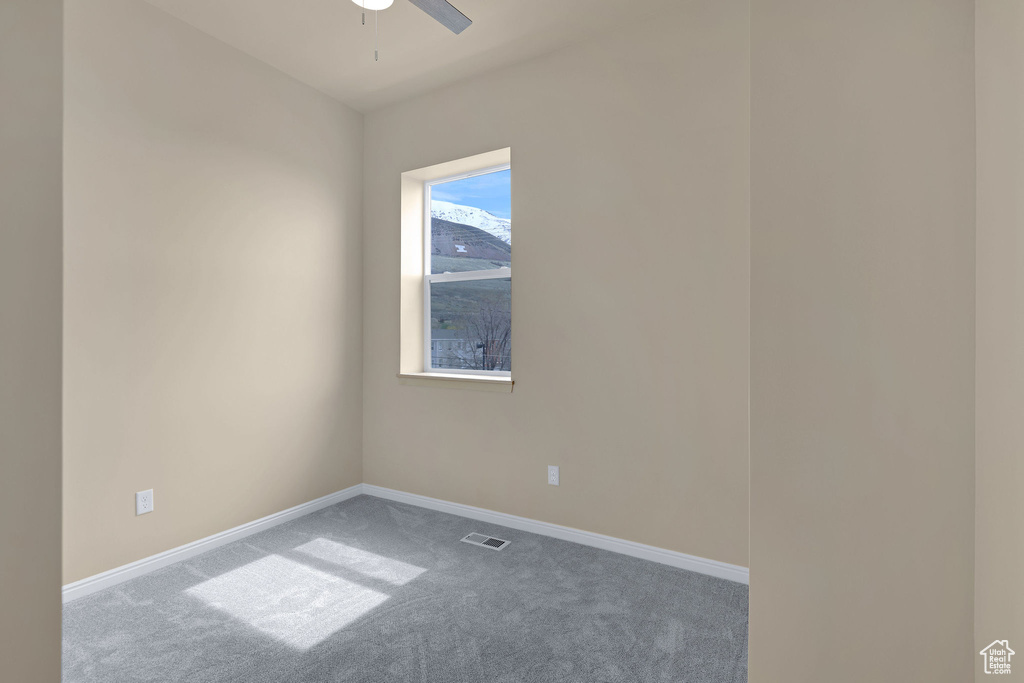 Carpeted empty room featuring baseboards and a ceiling fan