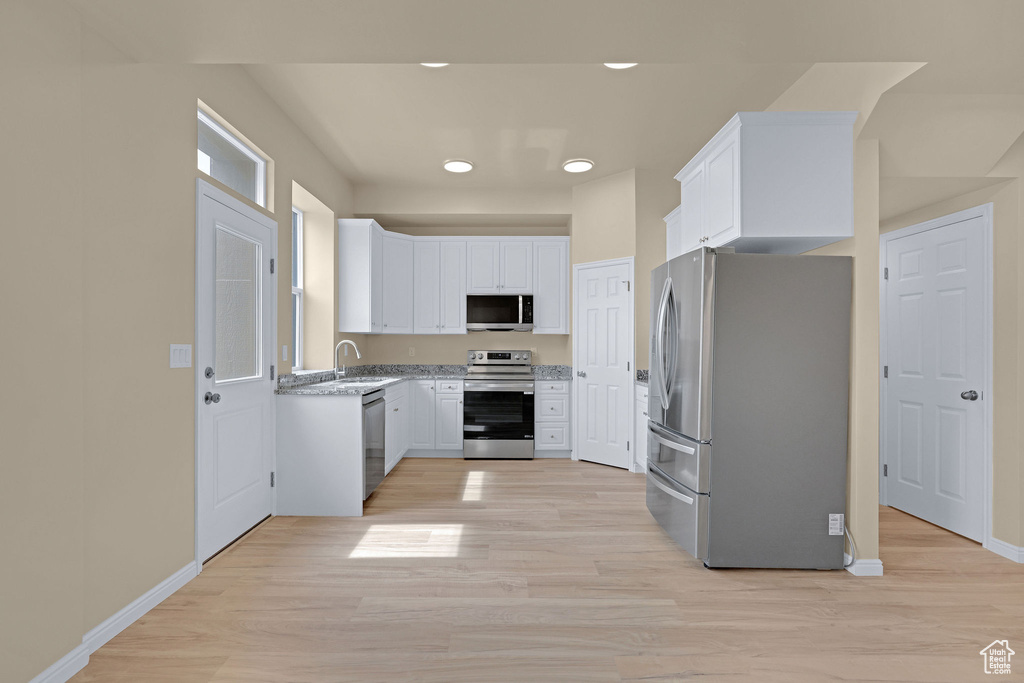 Kitchen with white cabinetry, light wood-type flooring, and appliances with stainless steel finishes