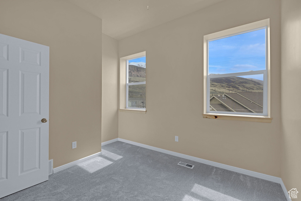 Carpeted empty room with visible vents and baseboards