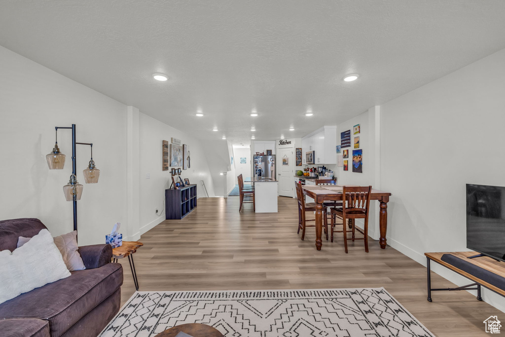 Living area featuring baseboards, light wood-type flooring, and recessed lighting
