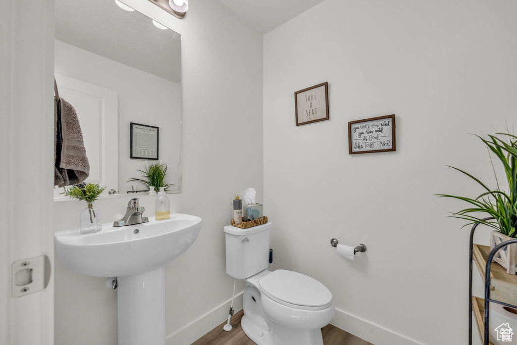 Bathroom featuring toilet, wood finished floors, and baseboards