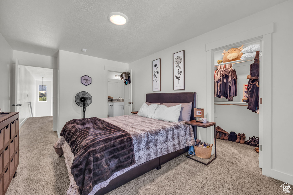 Carpeted bedroom featuring a closet, a spacious closet, and a textured ceiling