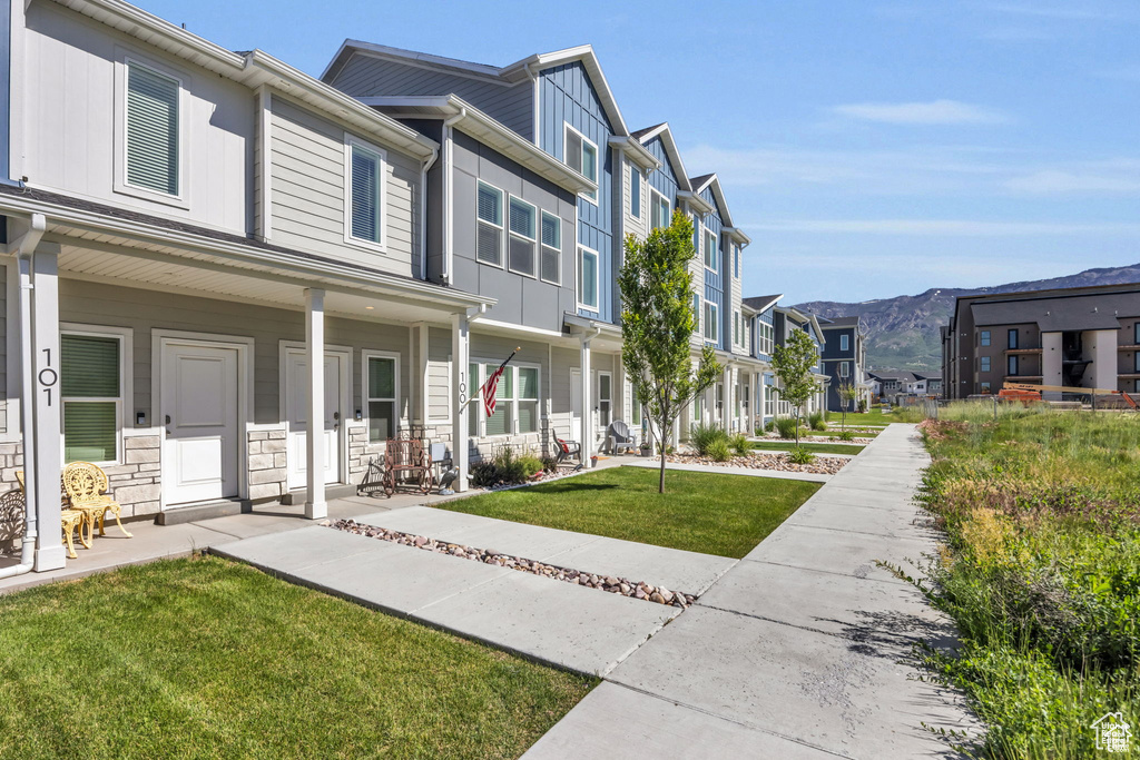 Exterior space with a residential view, a mountain view, stone siding, a front yard, and a porch