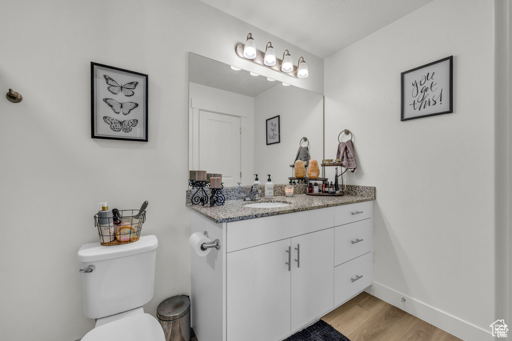 Bathroom featuring toilet, wood finished floors, vanity, and baseboards